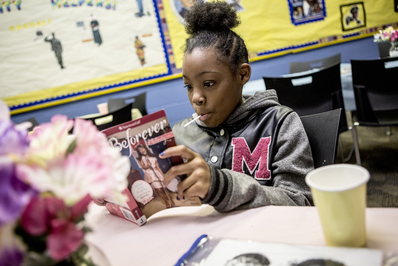 Jernya, 11, reads from one of her books while hanging out at the Cornelia Crenshaw Library.