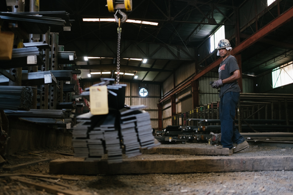 A worker lifts a stack of material with an overhead crane at Southern Steel. (Brandon Dahlberg)