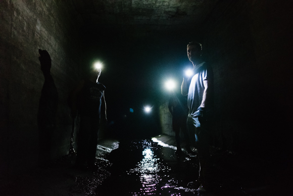 Four urban explorers make their way up the Gayoso Bayou, navigating by flashlight. (Brandon Dahlberg)