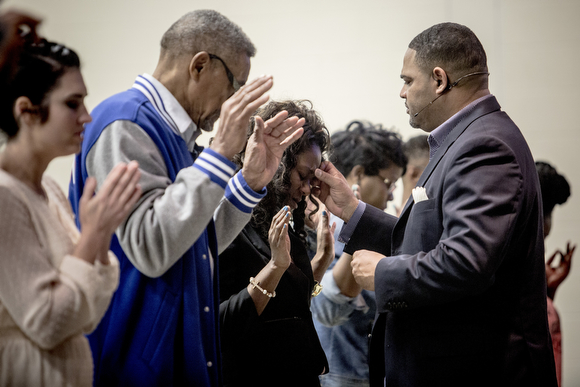 Pastor Colley Cooper blesses people on the forehead with some holy water during Sunday service at Hope City Church in Caldwell-Guthrie's cafeteria in Smokey City. 