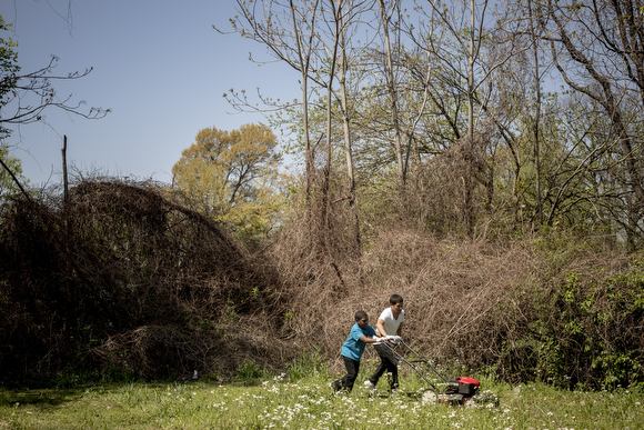 Jason Ayers helps Yalon Wallce, 10, mow through the high grass and weeds in an empty lot on Randle Street in Klondike. Folks from the community organization Crowning Our Youth, Inc. an anti-violence and youth oriented group, worked to clean up vacant
