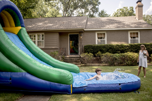  Epic Bouncing clients test out the slide and pool after it was set up in their yard for a party. 