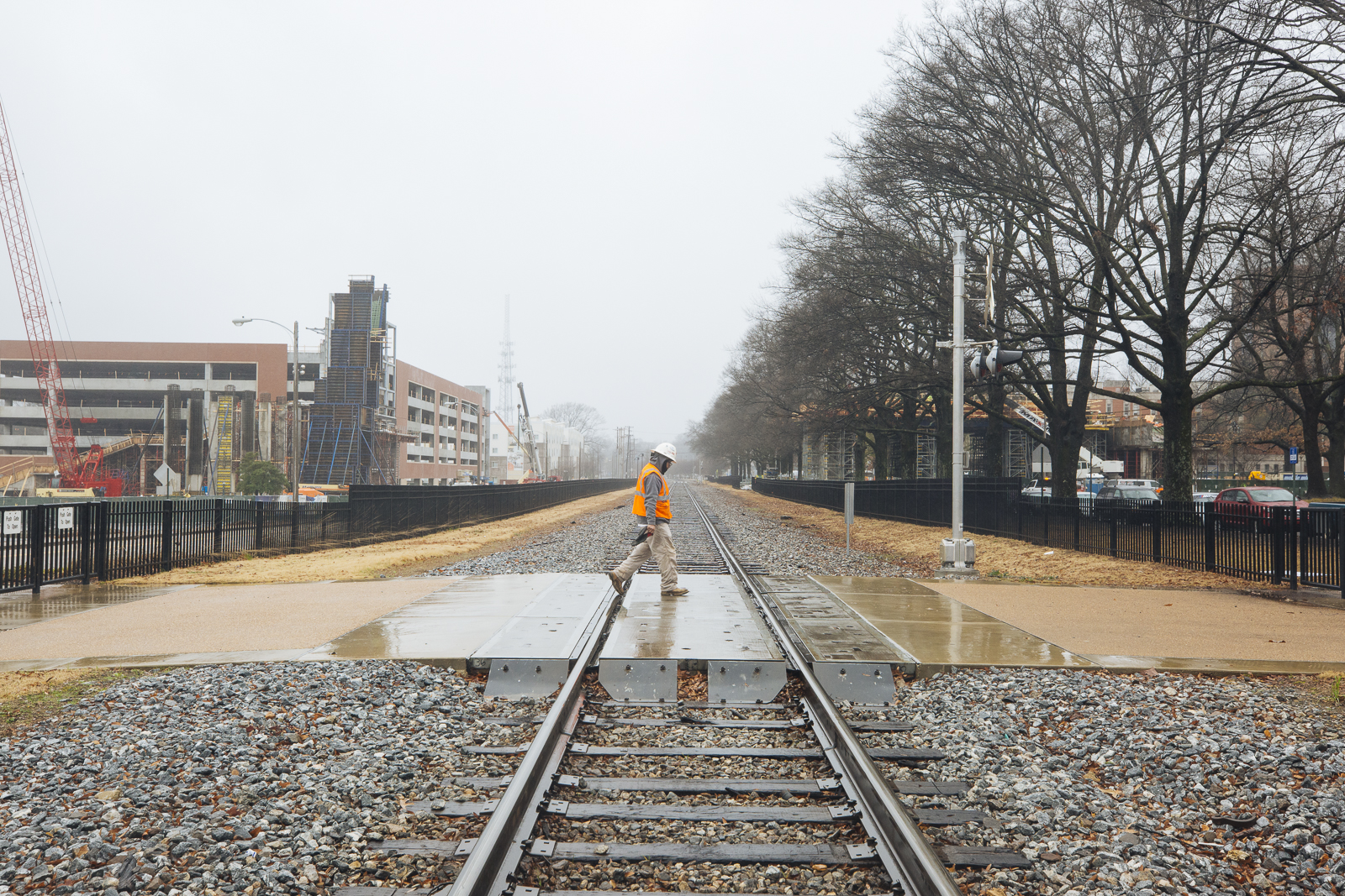 A construction worker crosses the train tracks at Southern Avenue. In the background, the University of Memphis' pedestrian bridge is under construction. (Ziggy Mack)