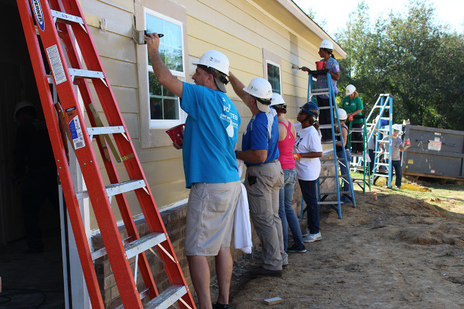 Volunteers and the actual home owners work on painting the new home in Oakhaven in S. Memphis.
