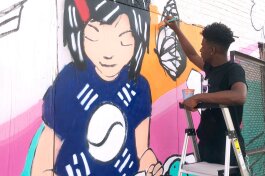 Donte Davis works on a section of the You's Grocery mural depicting store owner Ae An Sartain as a child when her father first opened the store. The artists based the mural on Sartain's memories and neighborhood history. (A.J. Dugger)