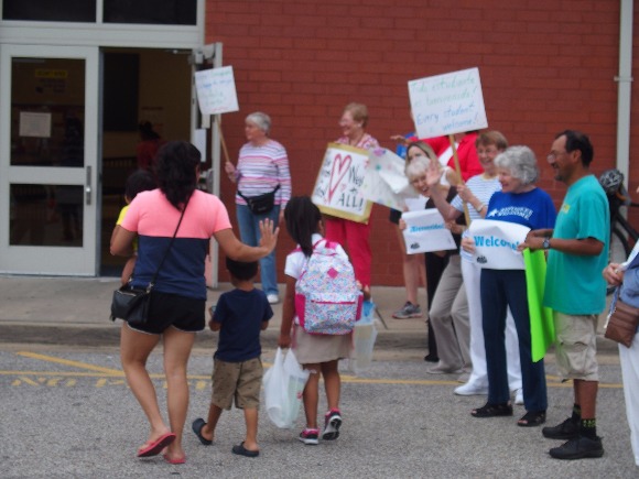 Neighbors, faith leaders and advocacy groups greet immigrant families arriving at Brewster Elementary School on the first day of class in Memphis
