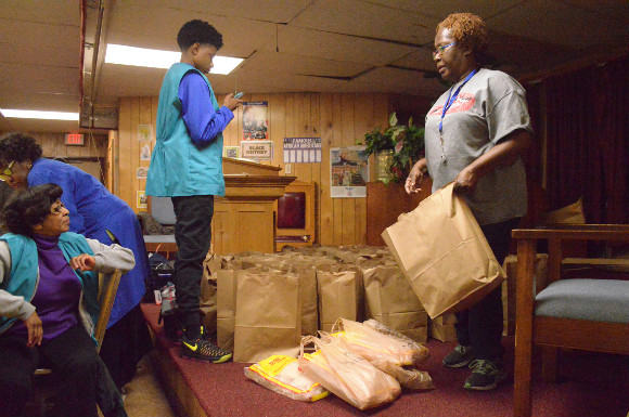Friendship Baptist parishioner Verdis McNutt assists with distributing much needed groceries to Klondike Smokey City residents who show up the church's Friendship Feeding Program.