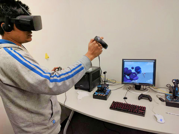 A VR user in action. What is displayed on the screen is a two dimensional representation of what is shown in a full three dimensions in the headset. Photo courtesy of Memphis Game Developers.