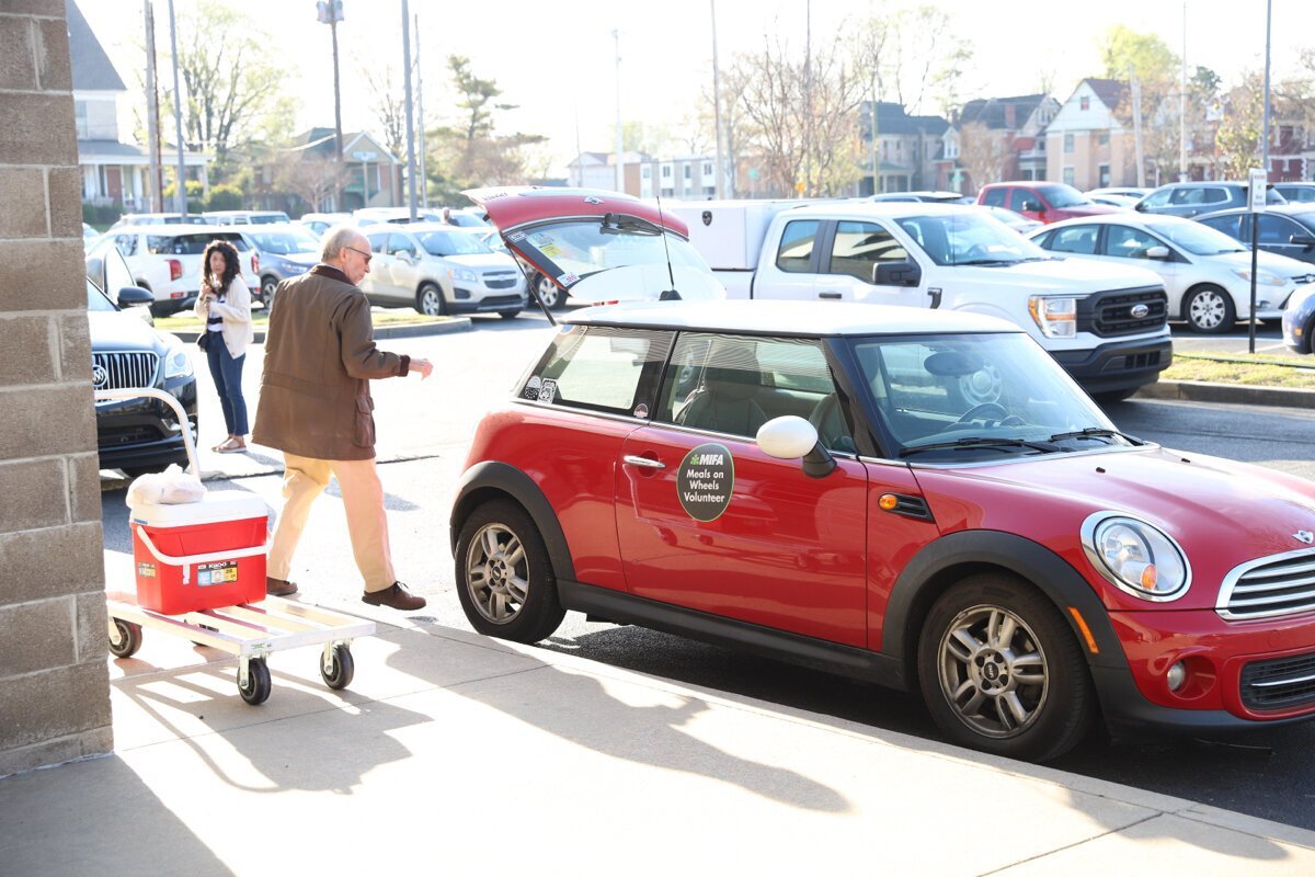 Volunteers load up their cars at MIFA headquarters as they prepare for another day’s delivery of Meals on Wheels.