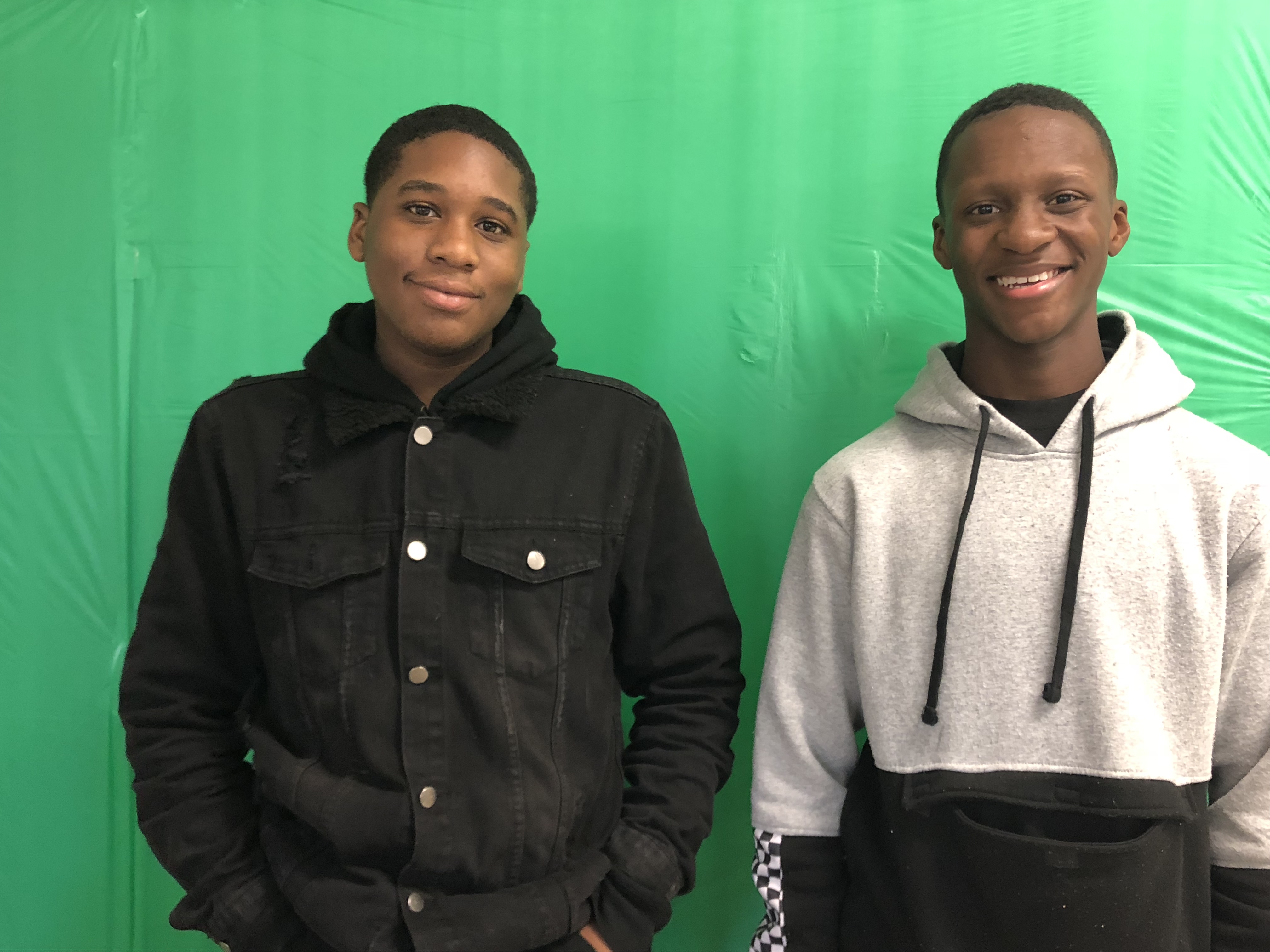 Staff writer and editor Nickcolus Blakemore (L) and staff writer Marquavious Wray pose in front of the new KHS Live! greenscreen. (Flying Falcon)