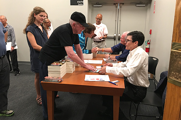 Dr. Jim Bailey (foreground) and Dr. G. Scott Morris sign copies of their books, while Dr. Clarence Davis (center background) answers questions from those who attended the inaugural Healthy City Town Hall meeting, held Sep. 16 at Novel bookstore.