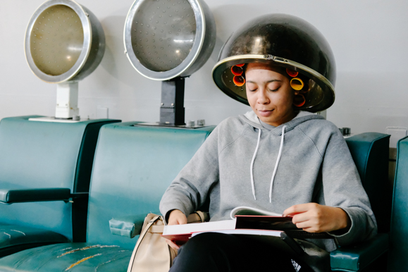 A customer at Hazel's Hair Fashions reads a textbook at the Whitehaven salon. (Brandon Dahlberg)