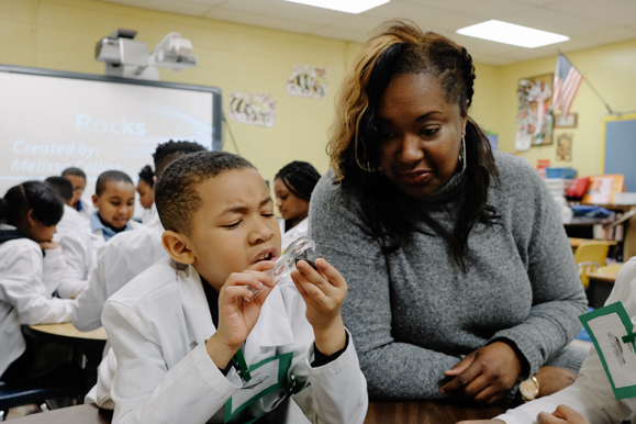 Johnathan Bush, 7, examines a rock during a science lession as Dr. Collins looks on. (Brandon Dahlberg)