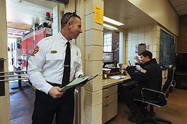 Twenty-year veteran Shane Howell (left) stops by with paperwork as Private Michael Pence (right) works the Station 18 desk where crew members field emergency calls and help citizen who walk in with an emergency. (Ziggy Mack)