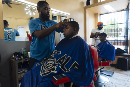 L to R: Upscale Kutz Barber Shop barbers Karlos Burt cuts the hair of Riko while Dennis Ross cuts the hair of Bernard in the Madison Heights District. (Ziggy Mack)