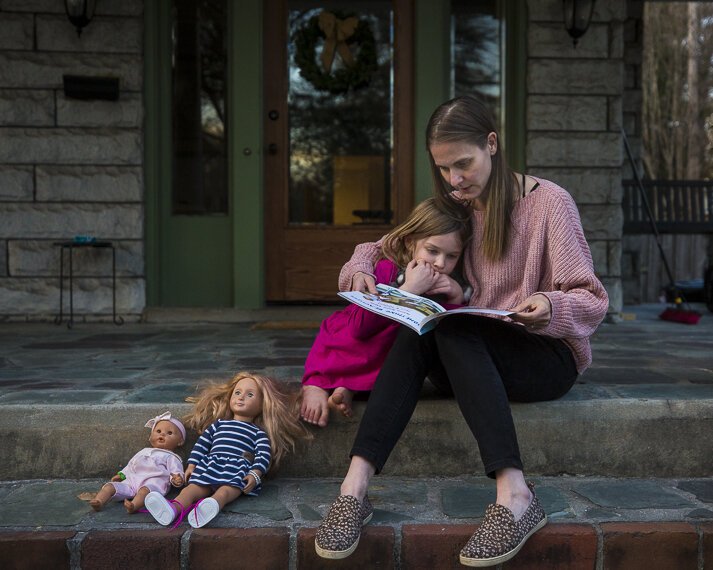 Victoria Kintner-Duffy reads to her daughter on the porch of their home in Central Gardens. (Ziggy Mack)