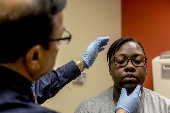  Dr. Narayanaswami Rangaswami, the pediatric physician at the Guthrie Primary Care Clinic in Smokey City, examines Christine Jones, 17. 