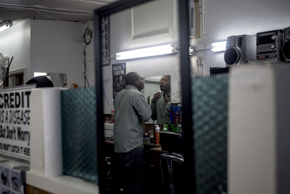 Derek Stubbs, a barber at the Handy Spot, trims his beard before sitting for a haircut. 