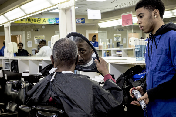 Jordan Butler lets a client check out his haircut at The Barber School on Jackson Avenue in Klondike. 