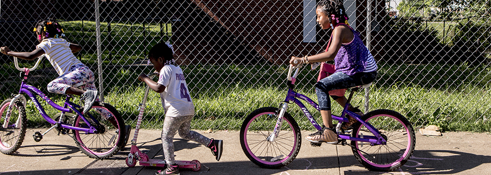 Girls ride their bikes down Tate Street.