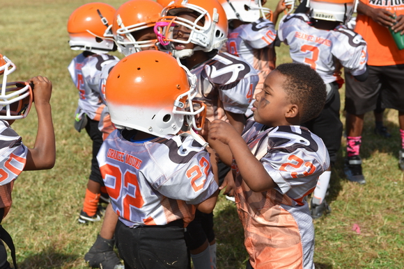 Teammates help each other adjust helmets as the Orange Mound Raiders prepare for a game. 