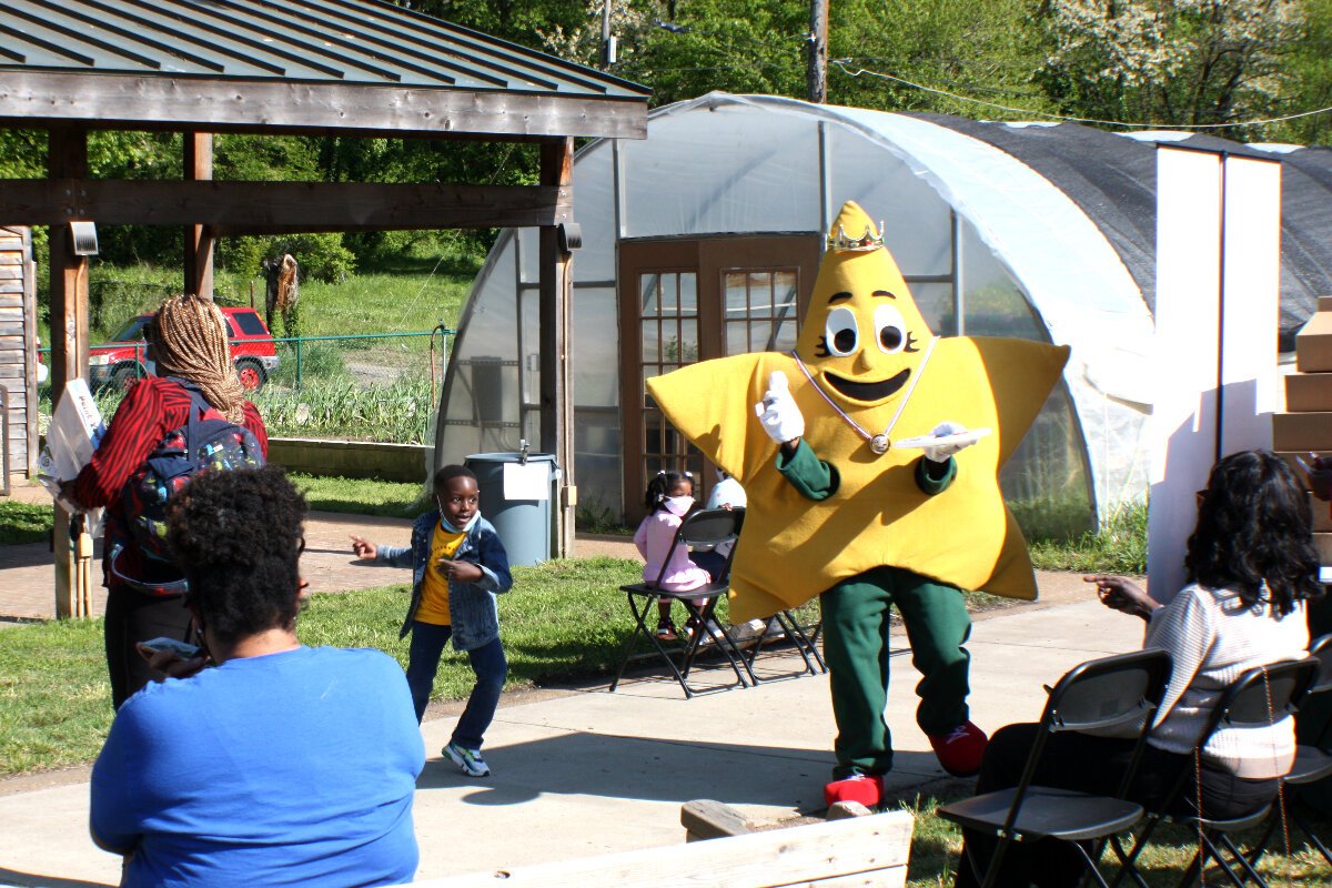 A young party goer and the mascot of the Paint It Clean bath kit dance to the music of the Jazz Brothers at the first Green Leaf Learning Farm Earth Day tour and tasting event, held on April 22, 2021. (Cole Bradley)