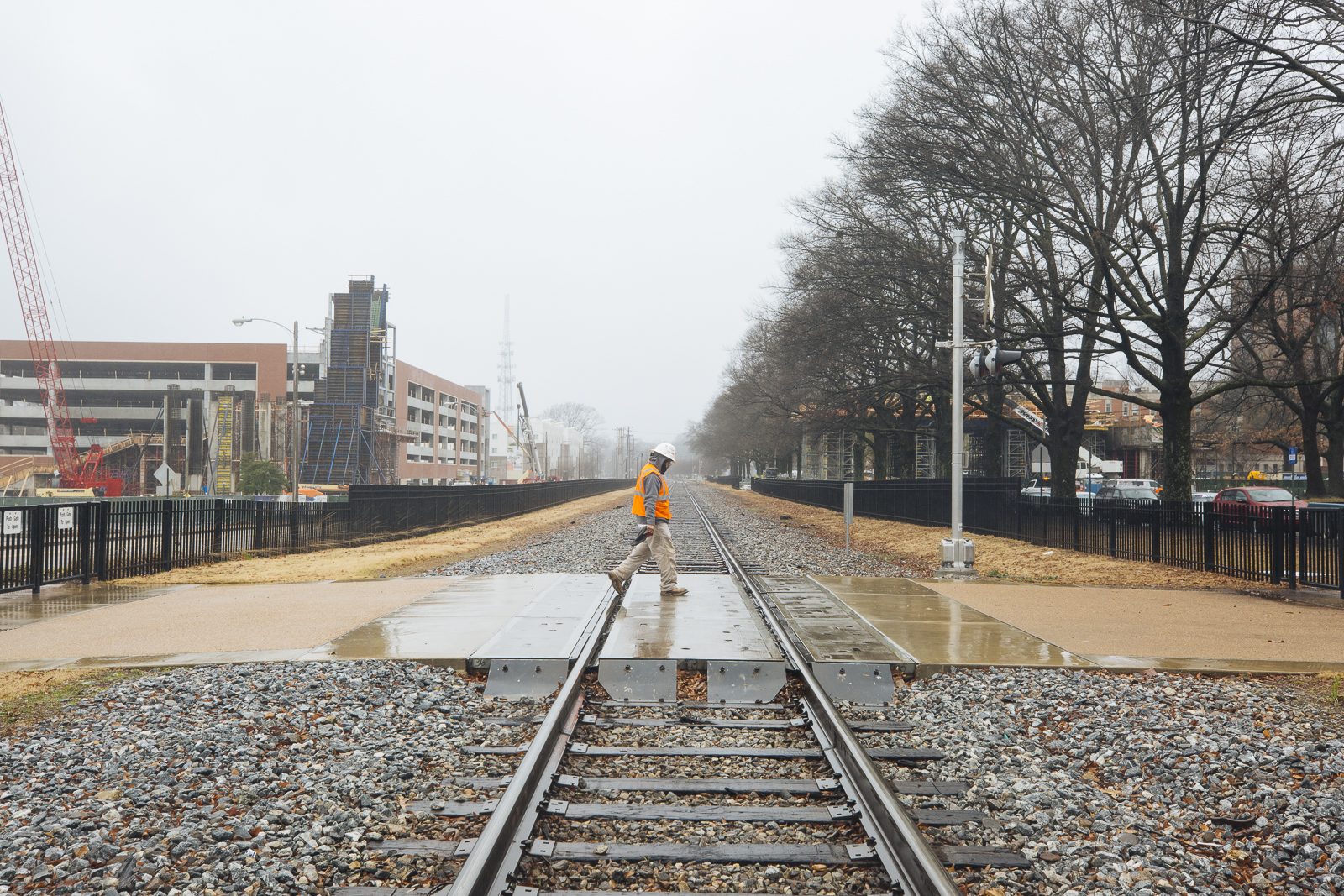 Construction worker traverses the crosswalk at the University of Memphis with the pending land bridge under construction in the far background. (Ziggy Mack)