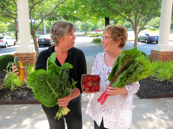 CSA subscribers Lorinda Hill (left) and Sandra Fortson compare notes on this week's haul, which features Swiss chard, strawberries and garlic scapes