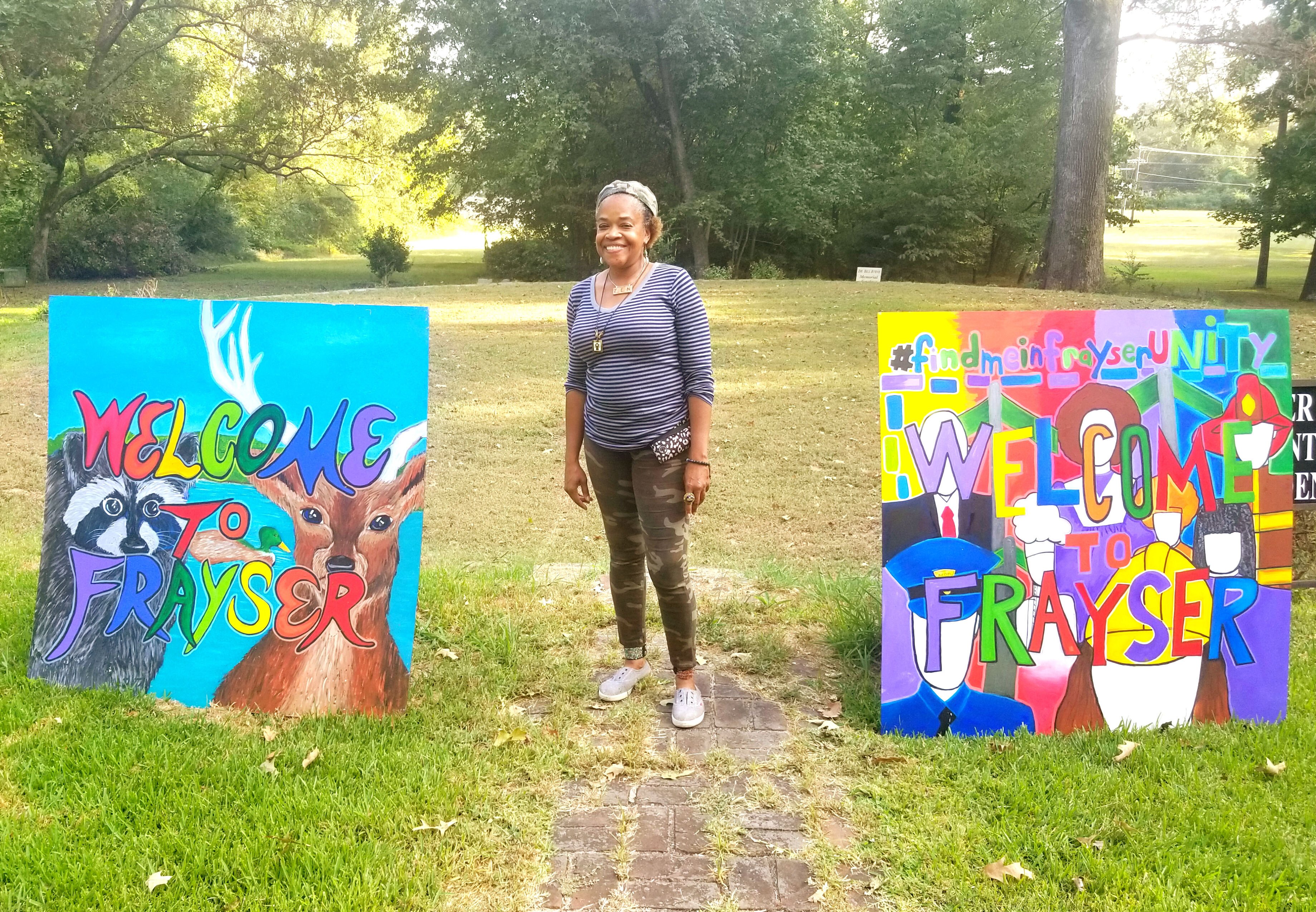 Frayser Local Arts Festival organizer Lurlynn Franklin stands next to two of five 'Welcome to Frayser' paintings. She designed the signs as paint-by-numbers and more than 700 Frayser residents had a hand in filling them in. (Arkwings Foundation) 