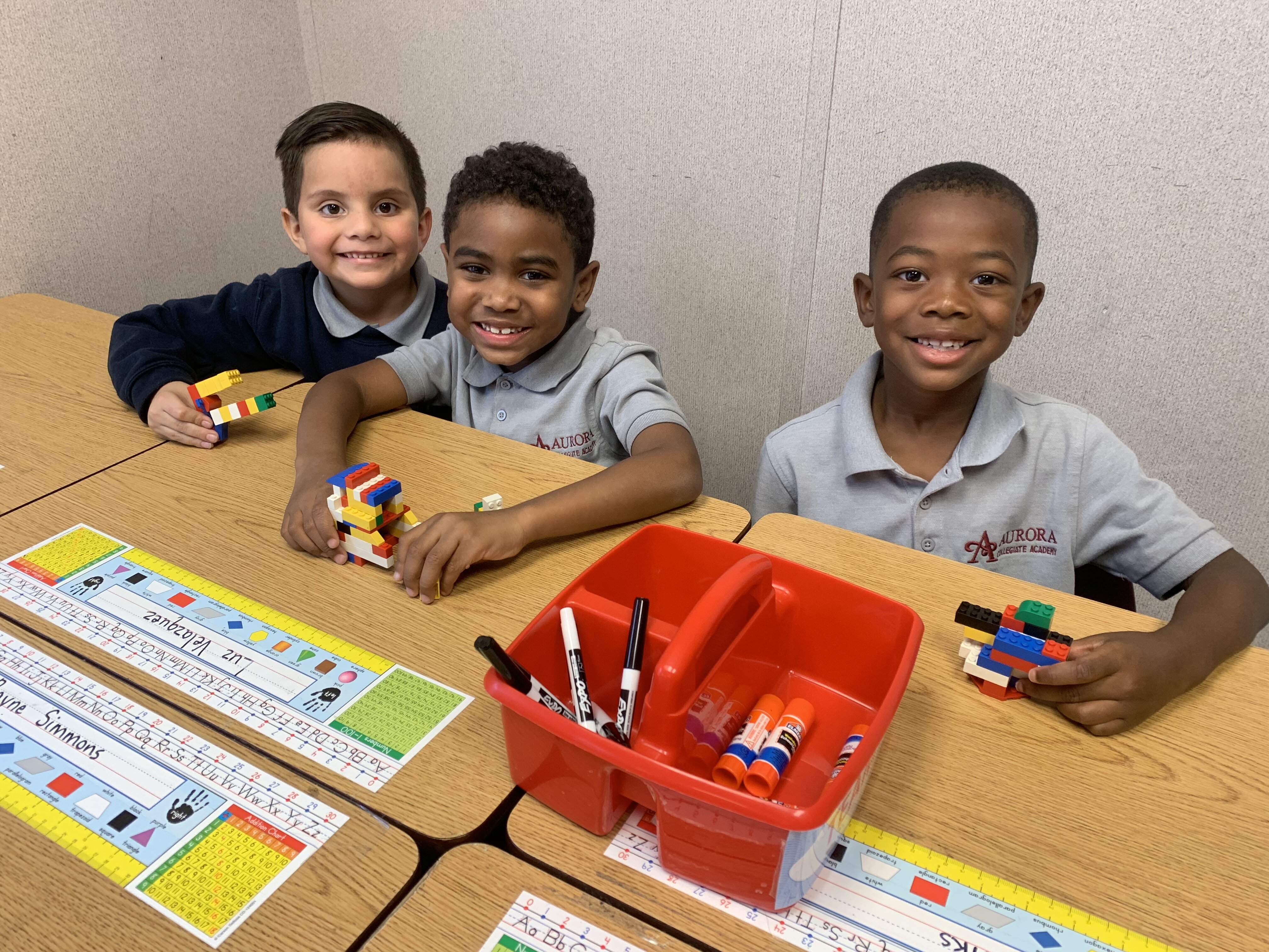 (L to R) Aurora Collegiate Academy first grade scholars Uriel Martinez, Roman Gibson and Jace Banks use brain break time to build skyscrapers. (Cat Evans)