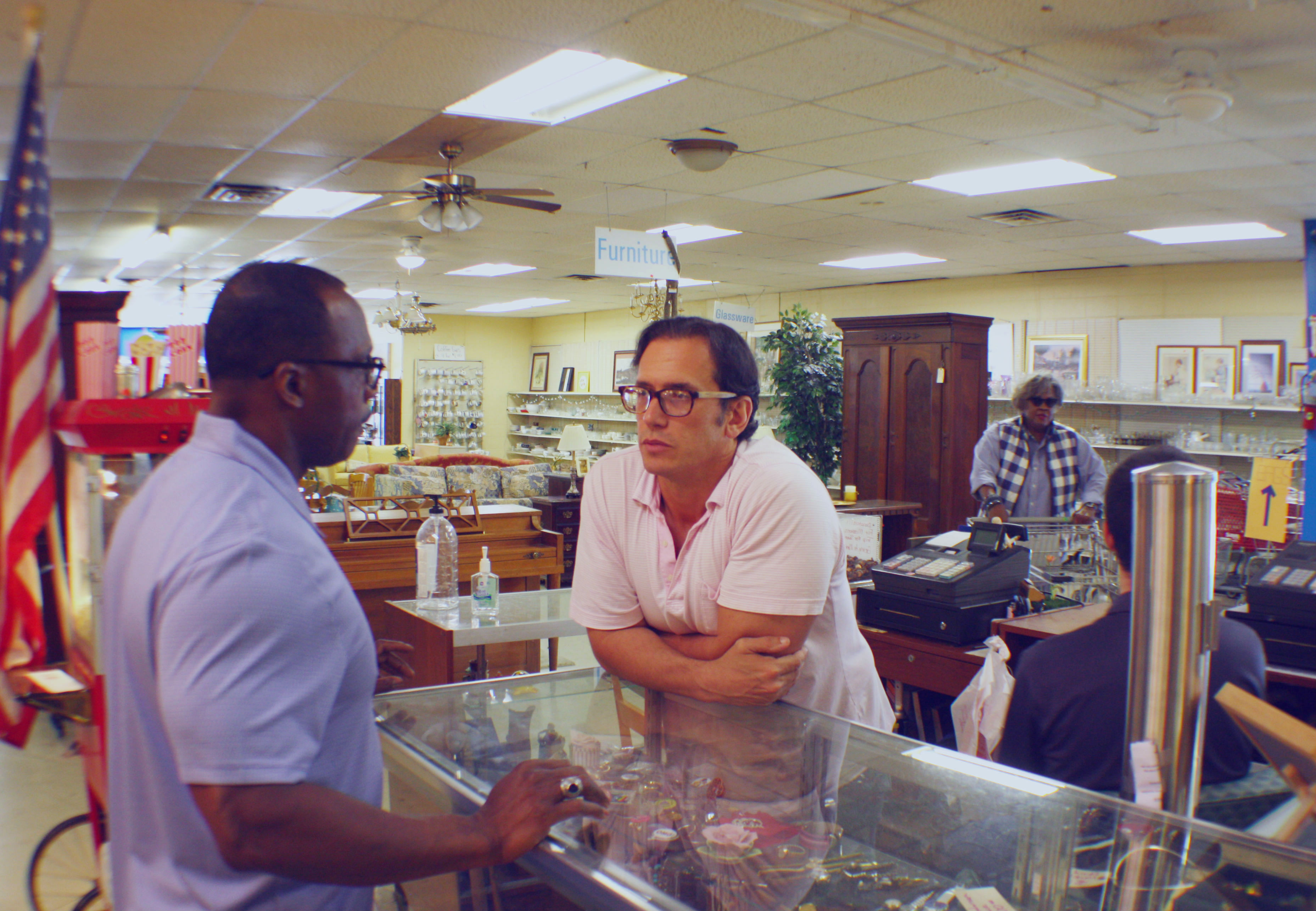 Anatole Williams (L), executive director of Memphis Adult Teen Challenge, and Michael Skouteris, daily operations manager of BAM Thrift Store, discuss store needs. To the right, regular Patricia Jones says hello to the cashier. (Cole Bradley) 