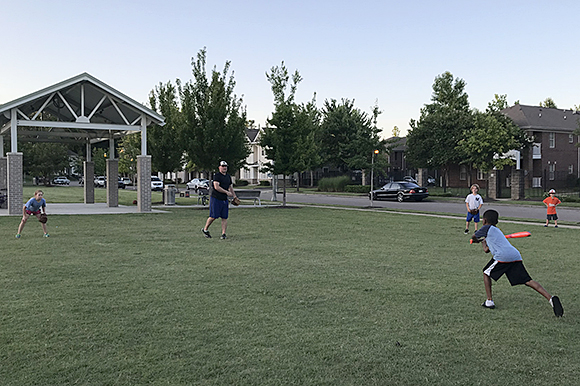 Nathan Sawyer pitches to his neighbor in an impromptu game of baseball at Uptown Park. 