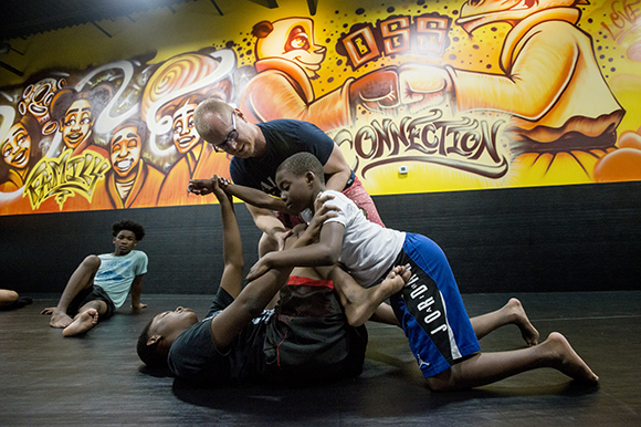 Lucas Trautman, top, demonstrates grappling technique with students Keyveyoun Chandler, 14, left, and Eric Booker, 11, at his Stardust Jiu-Jitsu studio in Binghampton. (Brandon Dill)