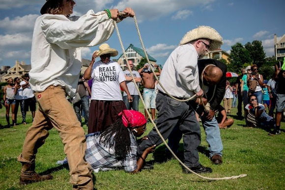 Folks participating in the street theatre performances at the Bridge Shut Down reunion act out a scene about punishment during slavery. 