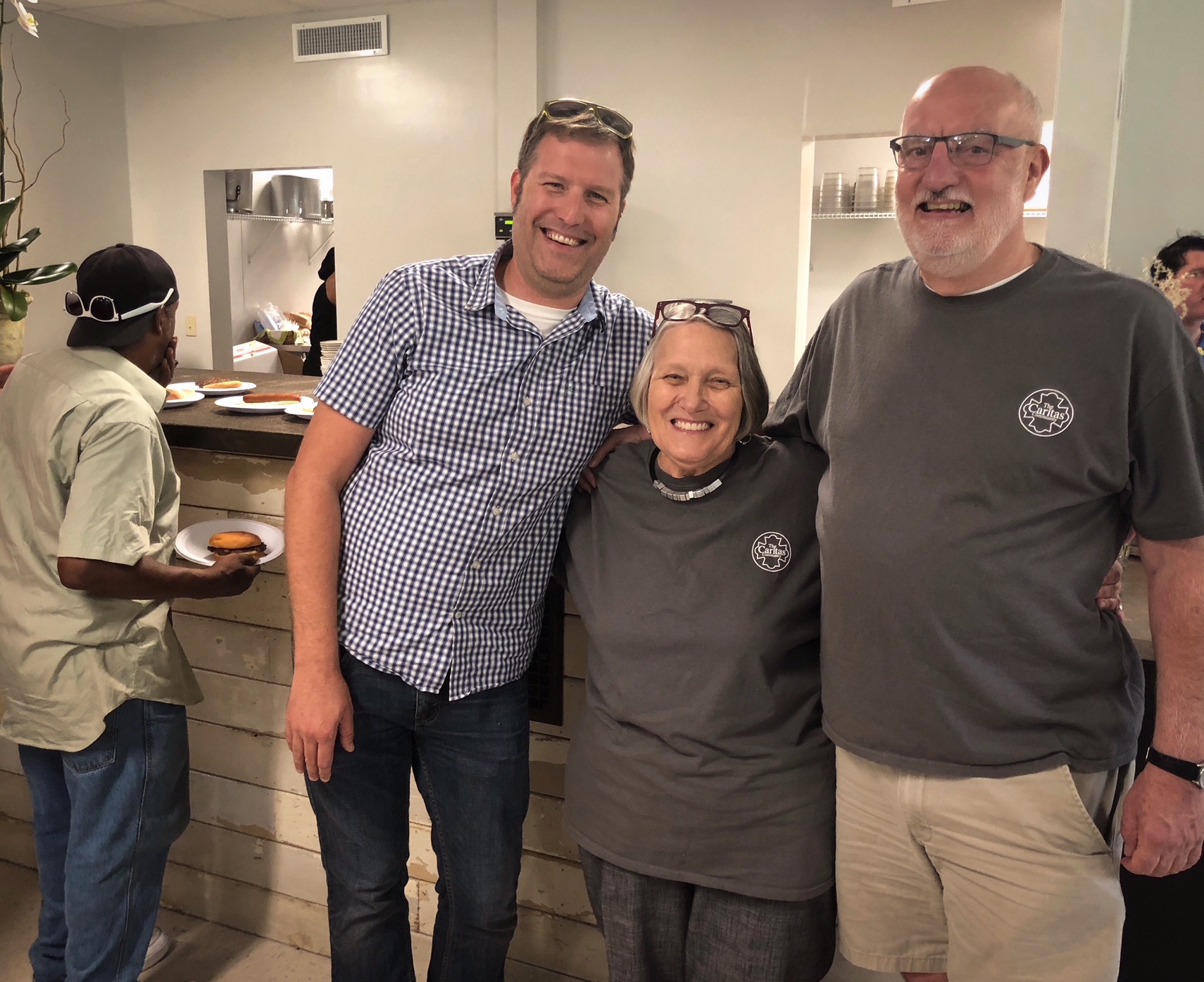 (L to R) Board member Peter Hossler, founder Onie Johns, and executive director Mac Edwards pose in front of the new cafe counter as a neighbor grabs a burger. (Shelda Edwards) 