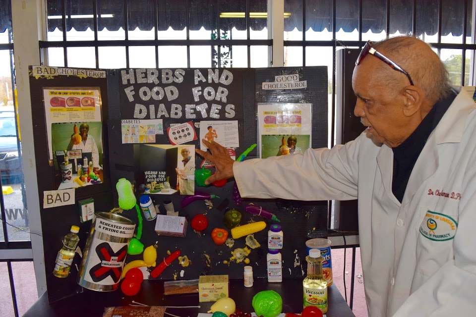 Dr. Champion and a display he made that features the proper foods and herbs for a healthy diabetic diet. (Rachel Warren)