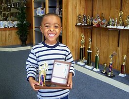 A child proudly displays an award at C & J Trophy and Engraving, located at 3444 Park Avenue in the Orange Mound-University District area. The business has been open since the 1970s. (C & J Trophy and Engraving)