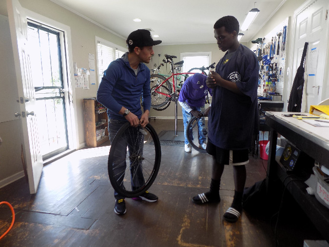 Pedaltown owner Clark Butcher works with  Binghampton youth on restoring a donated bike.