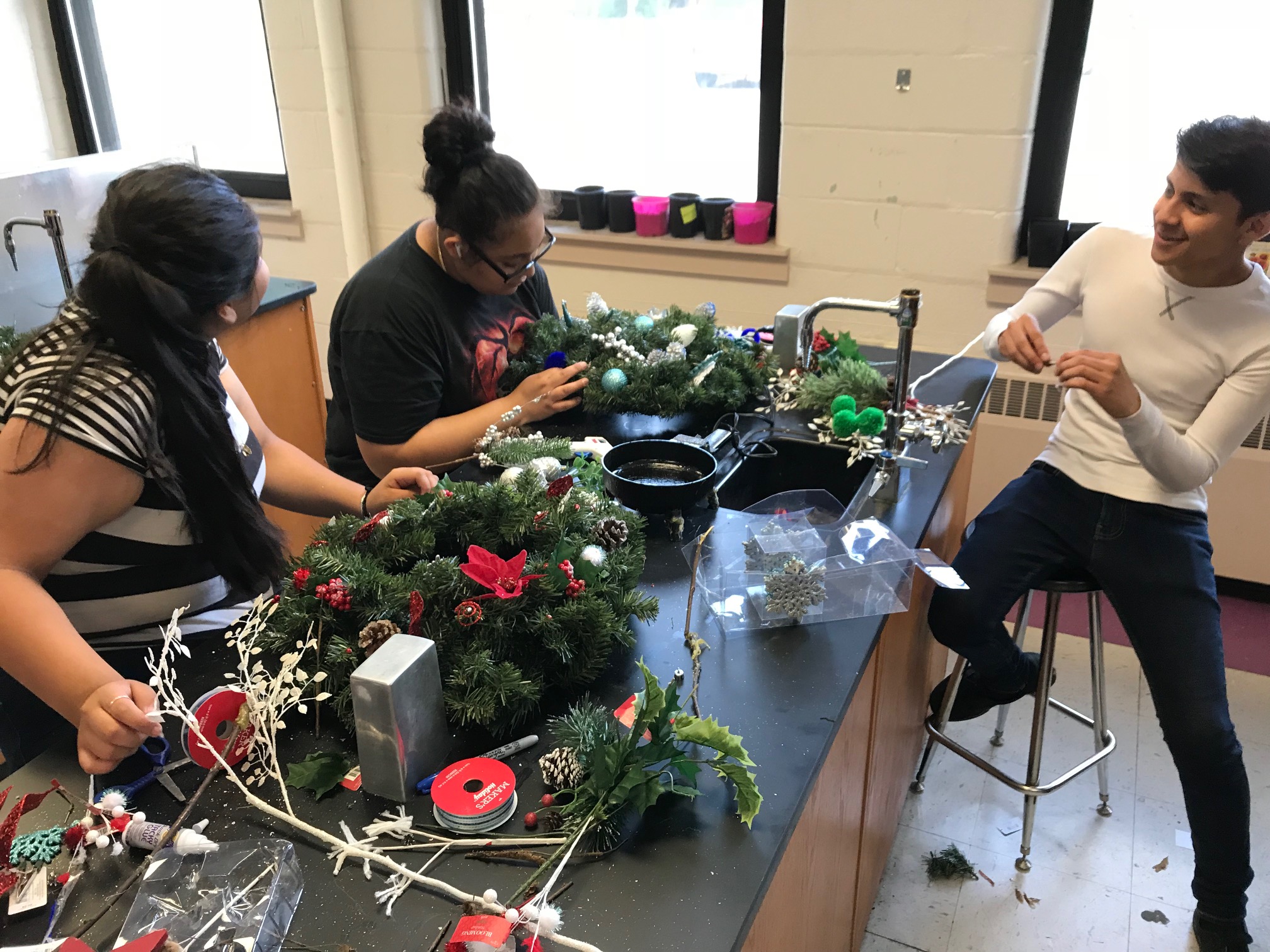 Student entrepreneurs Kimberly Rodriguez Moreno, Angie Vega, and Geronimo Ponce work on wreaths to sell at the market on July 28. (Cole Bradley)