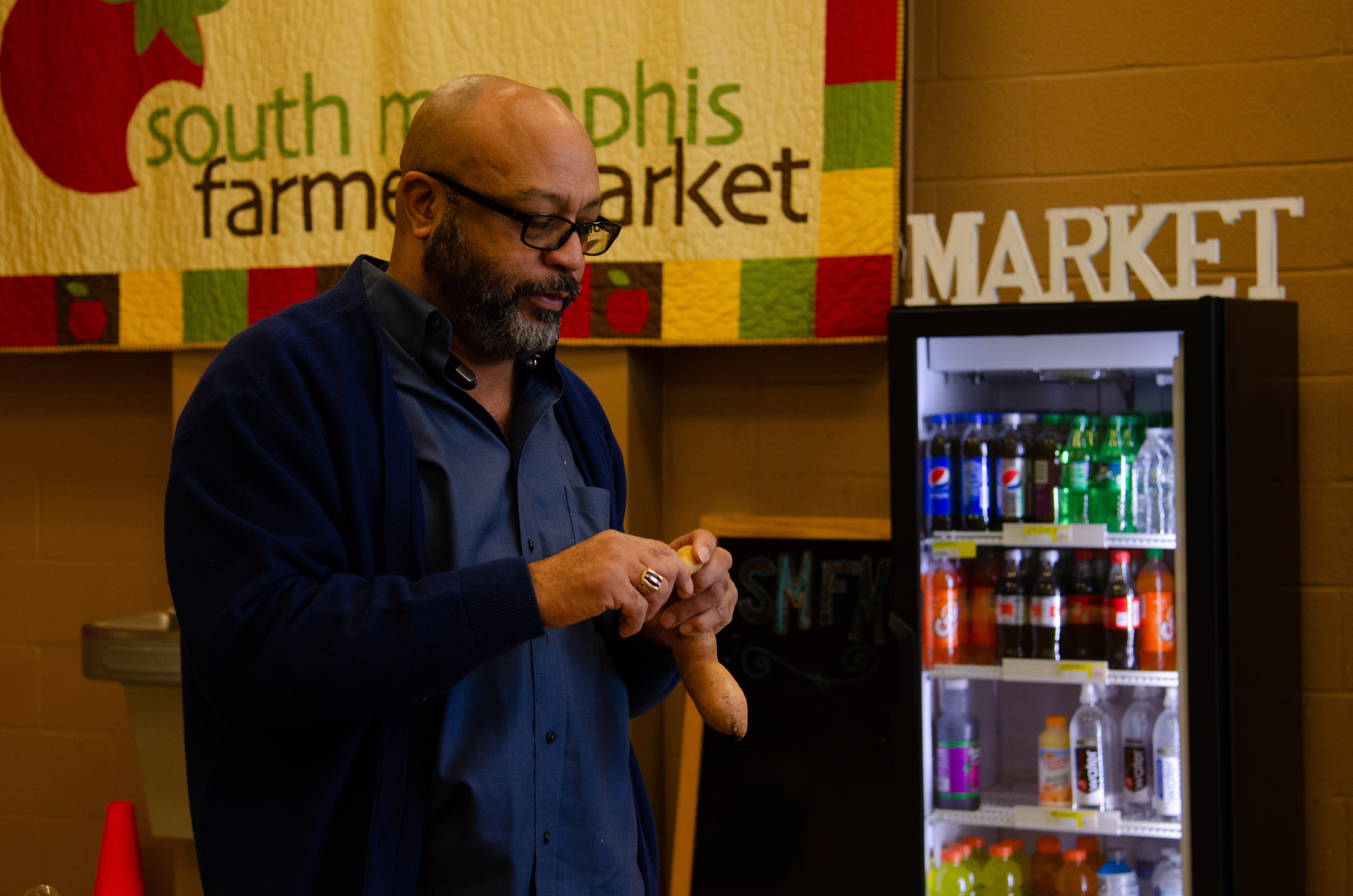 The Grocer store manager Devin Marzette inspects a sweet potato. (Cat Evans)