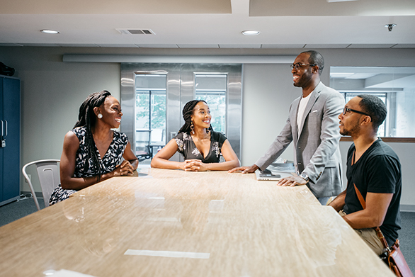 Mozak team members Tamara Reed, Jameelah Jordan, Justin Jackson, and Kevin Jordan gather around a conference table after a meeting at Start Co. in Downtown Memphis.