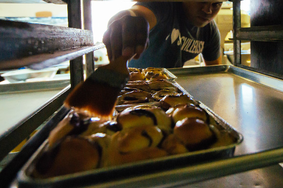 Daniel Watson, owner of Beneva Mayweather Foods, glazes cinnamon rolls.