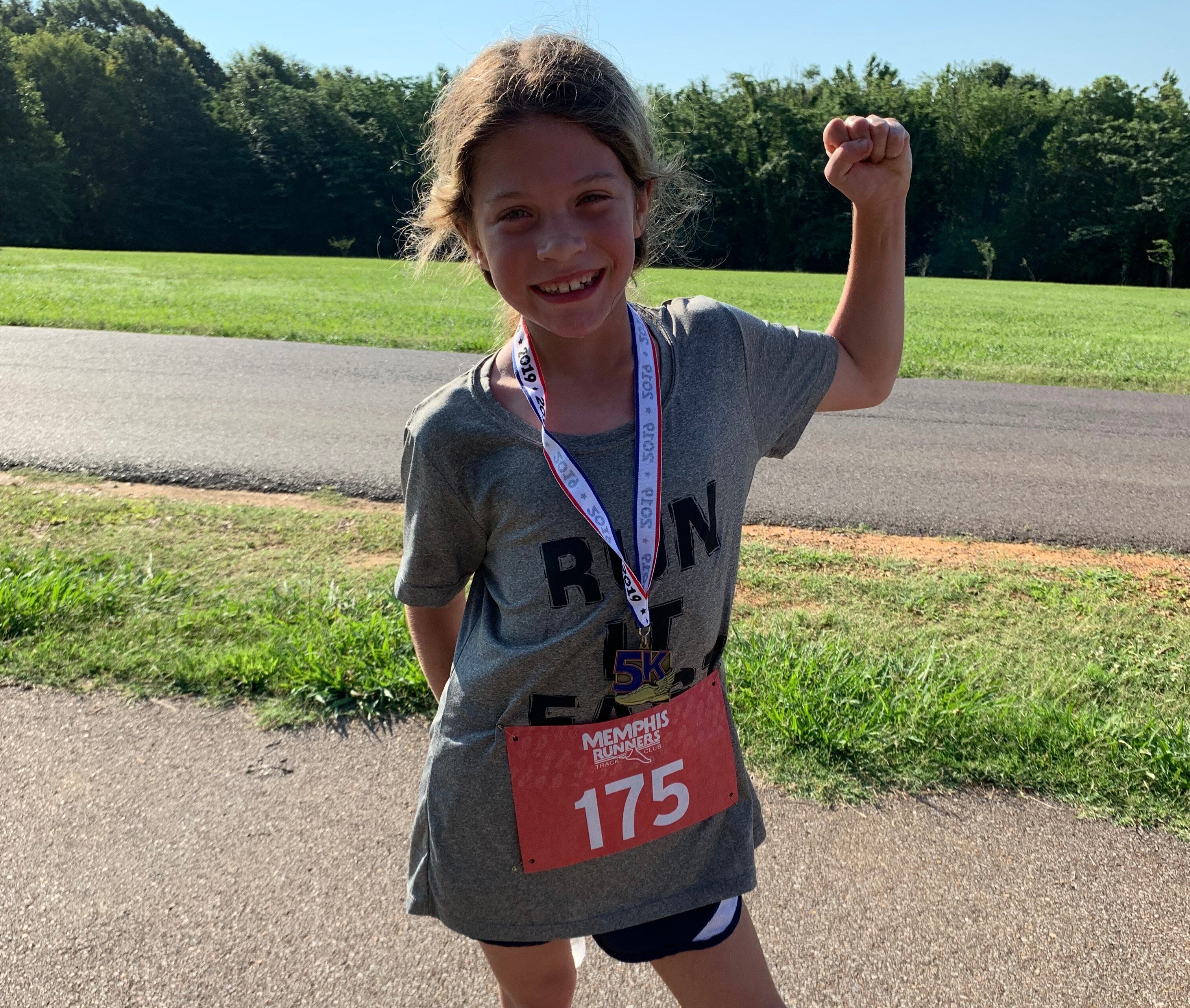 Juleann Roberts flexes her muscles after taking first in the youth division of The Hagar Center 5K Fun Run. (Ashlei Williams)