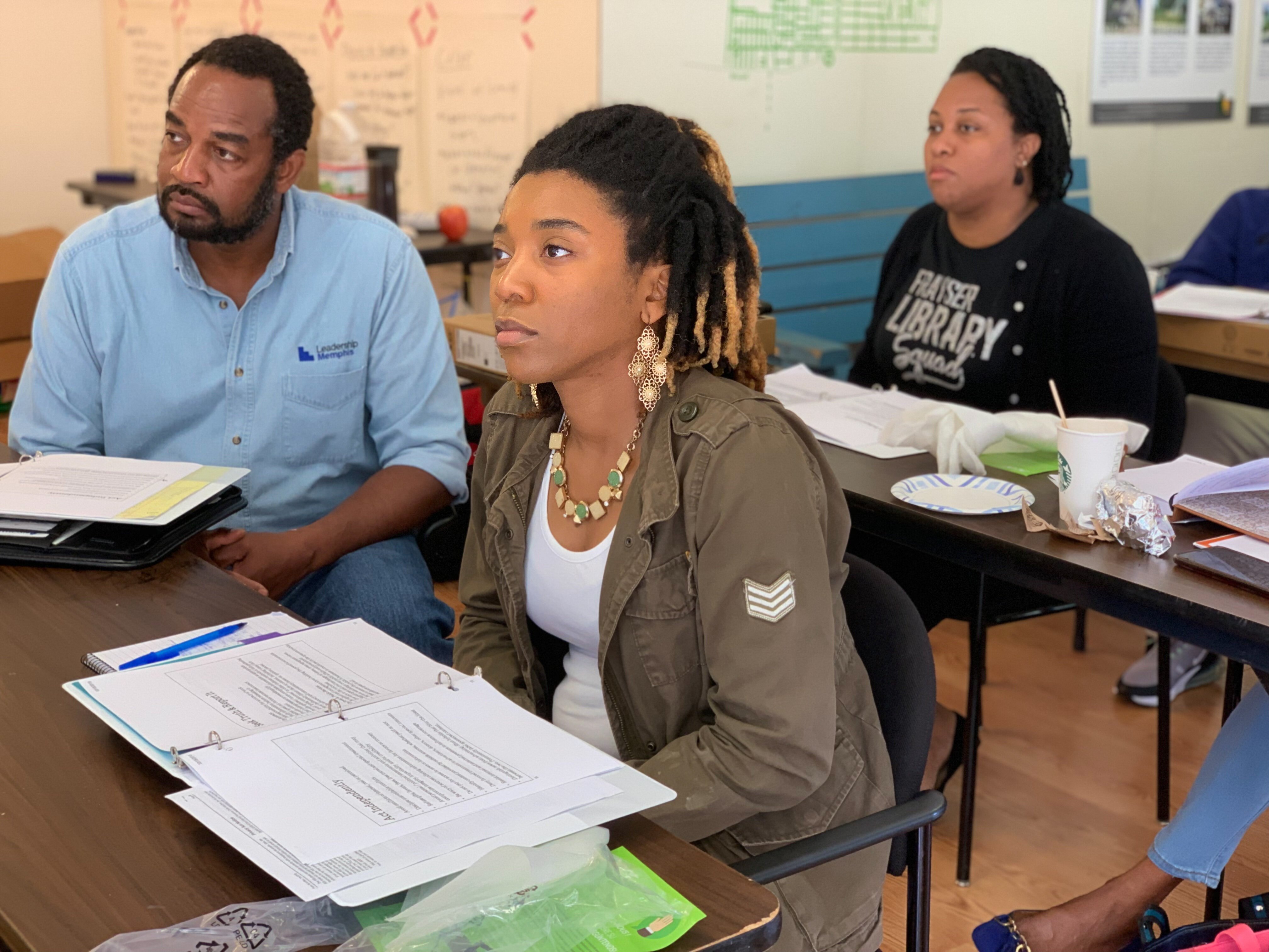 L to R: Community Correspondents Ian Randolph, Ivy Arnold, and Monique Rials listen attentively to a conversation on journalist ethics lead by trainer, Micaela Watts. (Cat Evans)