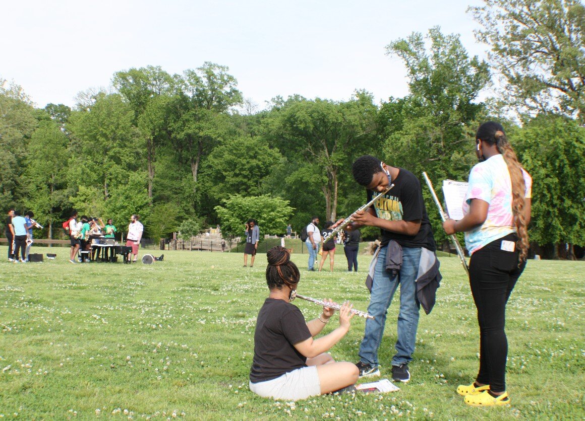 On the greensward at Overton Park, members of the Central High School band take a few extra minutes to practice their parts as the rest of the band wraps up practice behind them. May 2021. (Cole Bradley)