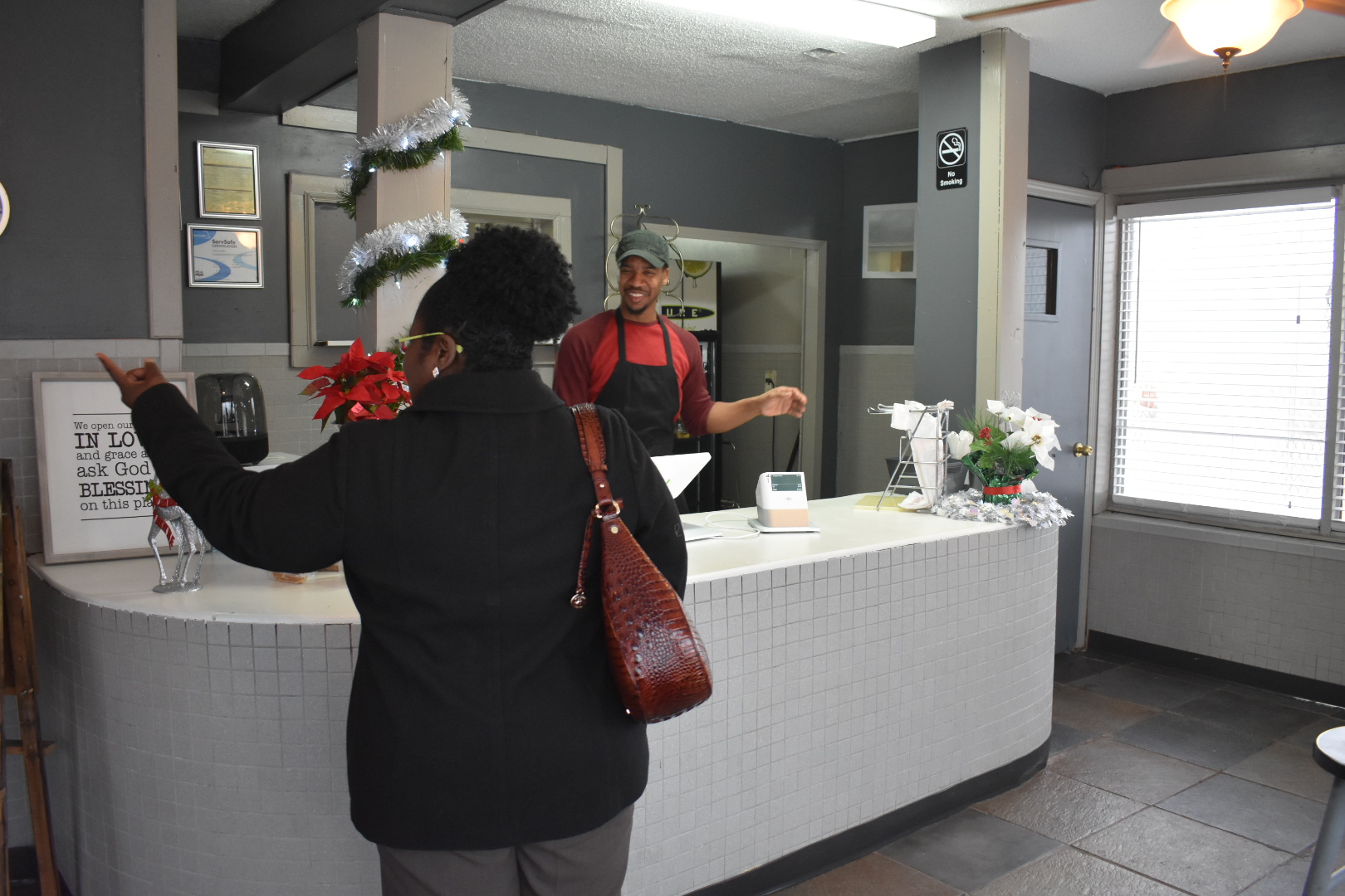 A customer points to the menu with a question and Tavias Ford answers with a smile at Vivian's Down Home Cooking in Binghampton. (Taylor Moore)