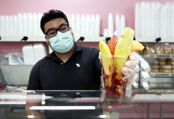 An employee of La Michoacana ice cream and paleta shop serves up a fruit cup with tajin. (Forever Ready Productions)