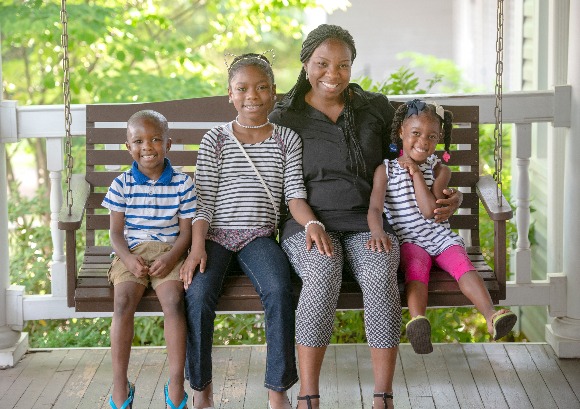 Hope House client and HIV advocate Latrina Moore and her three children pose for a portrait on the Hope House swing. Her two youngest children have attended Hope House's daycare and pre-K. (Greg Campbell)