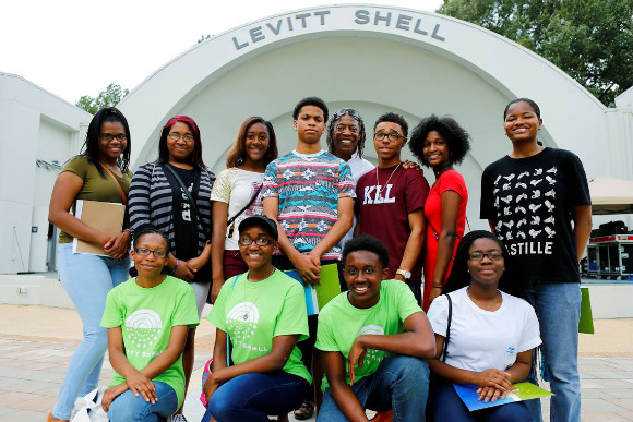 Nakia Poole (top row, next to last from left) stands with other Next Generation apprentices and Henry Nelson at the Levitt Shell.