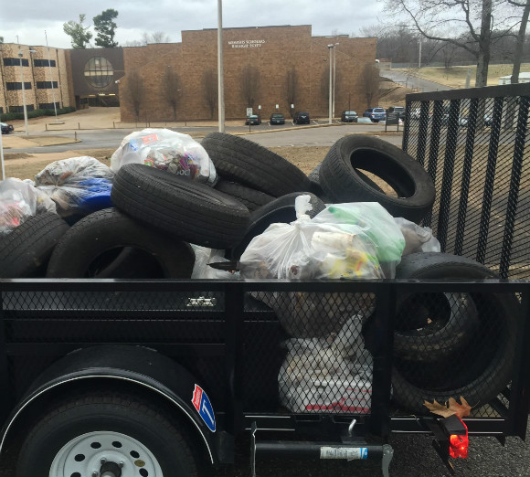 A work crew clears tires and trash from outside the Memphis Scholars Raleigh-Egypt school.